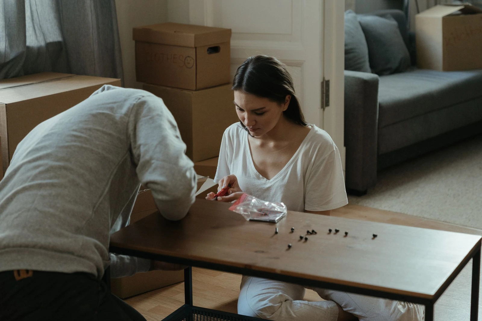 Couple assembling a wooden coffee table among moving boxes in their new home