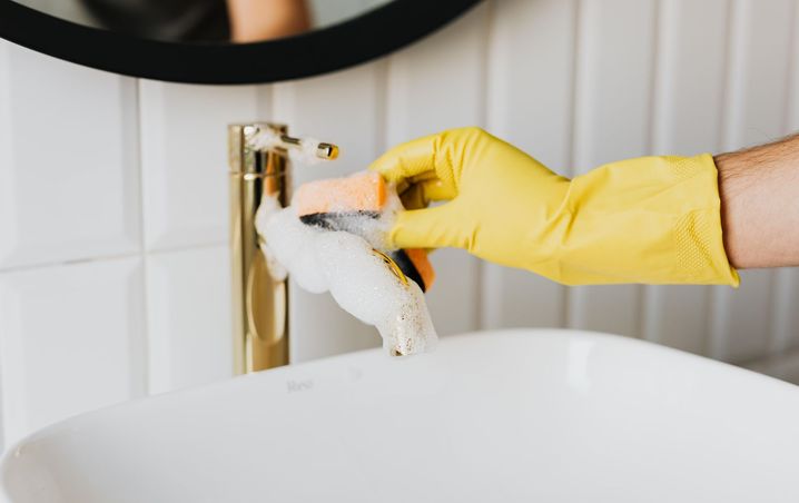Bathroom faucet covered in cleaning foam before rinsing